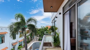 Ein Balkon mit Blick auf ein Schwimmbecken, Palmen und benachbarte Gebäude.