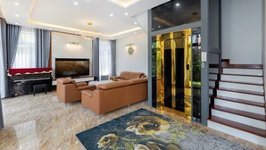 Ein modernes Wohnzimmer mit einem Klavier, Sofas, einem Fernseher und einer Treppe.