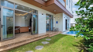 Ein modernes Haus mit Glastür, Schwimmbad und gepflegtem Rasen.