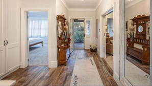 A hallway with wooden flooring, a white door leading to a balcony, and a mirror on the right. - Botanical Gardens Retreat | CBD walking distance (Albury)