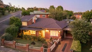 A two-story house with a brick exterior, a covered porch, and a well-maintained lawn. - Botanical Gardens Retreat | CBD walking distance (Albury)