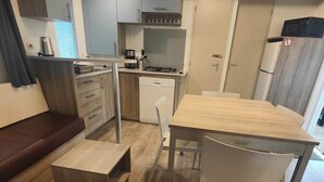 Una cocina compacta con comedor, un refrigerador pequeño y un horno empotrado.