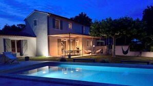 Una casa moderna con piscina, mobiliario exterior y un jardín bien cuidado.