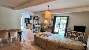 Un espacio de sala amplio con un sofá grande, una mesa de comedor con sillas y una cocina al fondo.