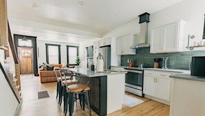 A modern kitchen with white cabinets, a central island with bar stools, and a built-in oven.