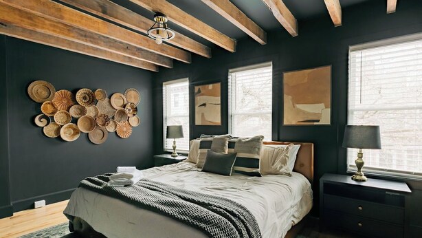 A bedroom with a bed, bedside tables, a wall of woven baskets, and artwork.