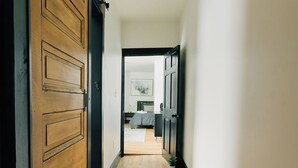 A hallway with wooden flooring and a large wooden door on the left.