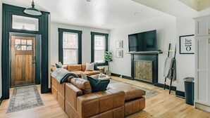 A modern living room with a leather sofa, a fireplace, and a large TV.
