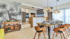 Een moderne keuken met een centraal eiland, houten stoelen en een eettafel gedekt voor zes personen.