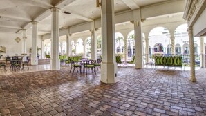 Un patio interior con suelo de ladrillo, columnas blancas y zonas de estar al aire libre.