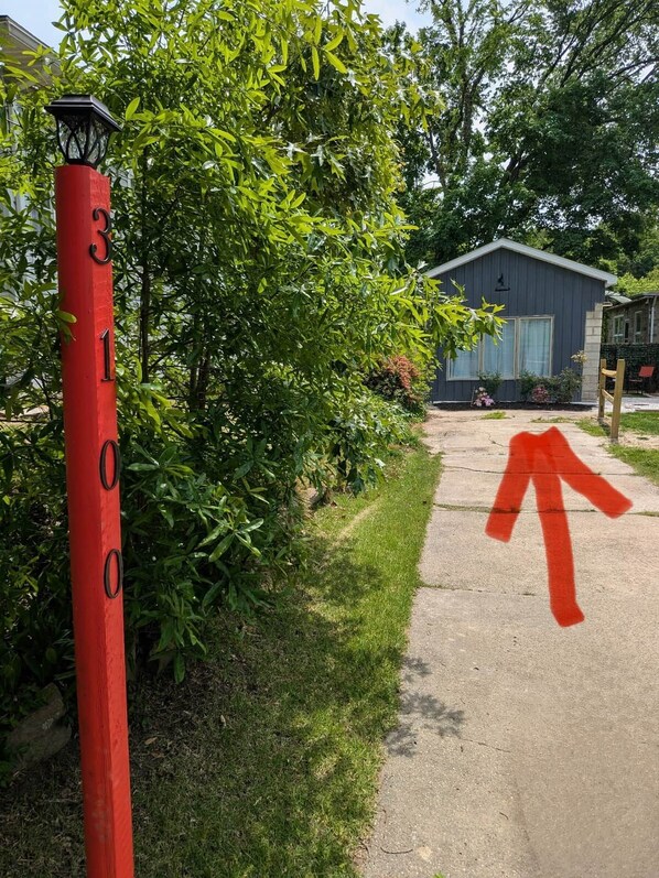 A red numbered post with a directional arrow, a pathway, and a building in the background. - Ruscincy’s Rest in Historic Arcadia-Beverly Hills (Baltimore)