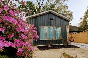A small, single-story building with a dark exterior and a pitched roof. - Ruscincy’s Rest in Historic Arcadia-Beverly Hills (Baltimore)