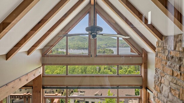 A room with a sloped ceiling, large windows, and a view of a lake. - Tremblant Prestige - Altitude 170-9 (Mont-Tremblant)