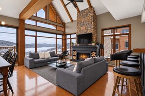 A spacious living area with a stone fireplace, large windows, and a high ceiling. - Tremblant Prestige - Altitude 170-9 (Mont-Tremblant)