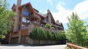A multi-story lodge with a stone facade, multiple balconies, and a driveway leading to a gated entrance. - Tremblant Prestige - Altitude 170-9 (Mont-Tremblant)