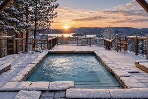 A hot tub surrounded by a wooden deck with snow-covered ground, overlooking a scenic landscape with a sunset. - Tremblant Prestige - Altitude 170-9 (Mont-Tremblant)