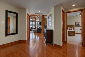 A spacious hallway with wooden flooring, a large mirror, and a view into a living area with a fireplace. - Tremblant Prestige - Altitude 170-9 (Mont-Tremblant)