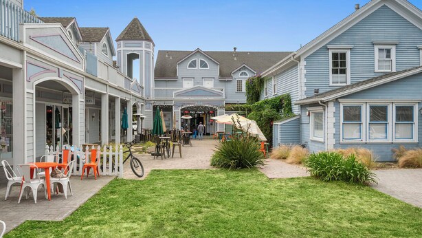Un patio con mobiliario exterior, una bicicleta y un edificio con entrada a una tienda.
