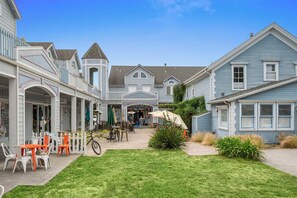 A courtyard with outdoor seating, a bicycle, and a building with a shop entrance. - Mavericks Penthouse – Downtown Luxury on Main Street, Half Moon Bay (Half Moon Bay)