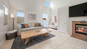Un salón amplio con chimenea, un sofá, una mesa de centro y un televisor.