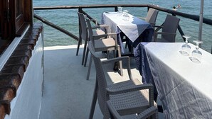 A deck with wicker chairs and a table set for dining, overlooking a calm sea with boats. - Right in the center of Ischia, the ideal villa for comfortable exclusive vacations (Ischia)