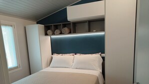 A bedroom with a bed, a headboard, a shelf with decorative items, and a door. - 5 minutes from the lake house with garden in residence with swimming pool (Padenghe Sul Garda)
