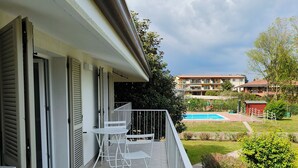 A balcony with a view of a swimming pool, a garden, and a building in the background. - 5 minutes from the lake house with garden in residence with swimming pool (Padenghe Sul Garda)