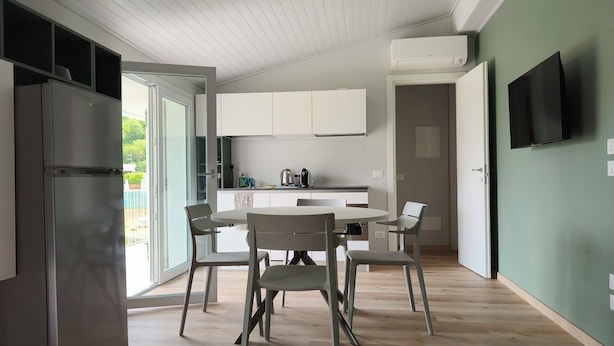A modern kitchen with white cabinets, a built-in oven, and a dining area with a round table and chairs. - 5 minutes from the lake house with garden in residence with swimming pool (Padenghe Sul Garda)