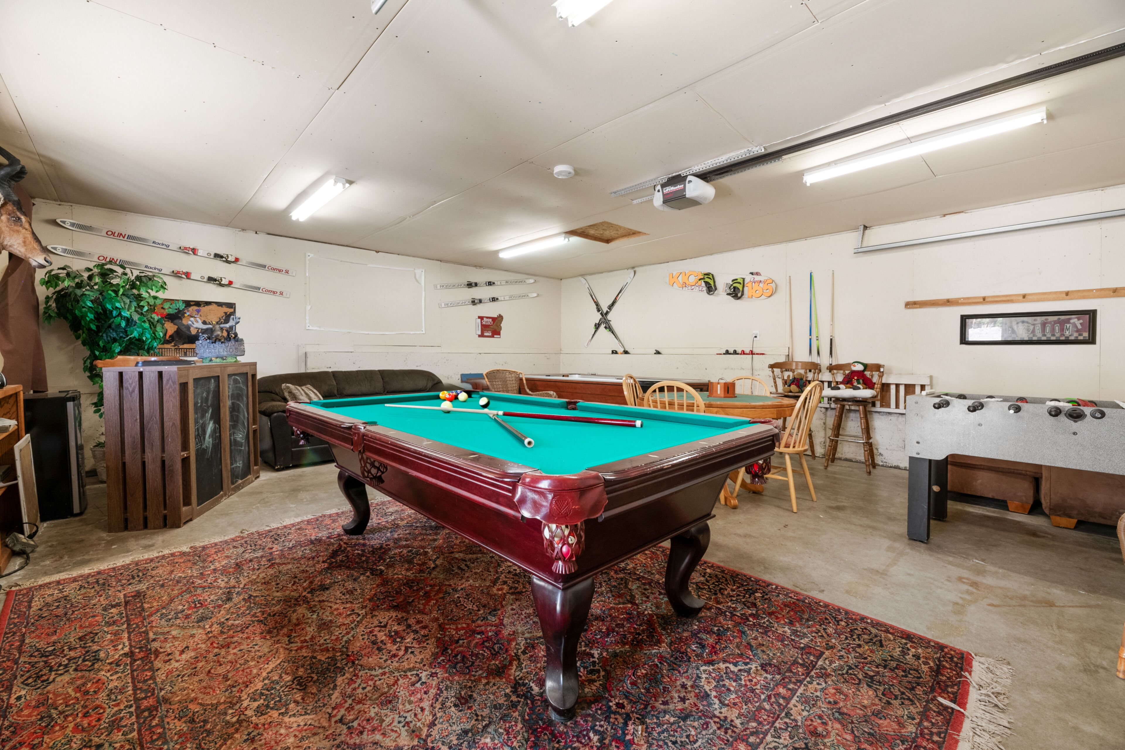 Une table de billard avec des billes, une table de baby-foot et un porte-queue de billard.