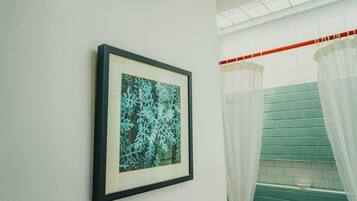 A framed artwork on a wall, a staircase with green tiles, and a white curtain.
