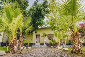 A building with a green facade, surrounded by palm trees and a gravel pathway. - Beautiful country house in Chiclayo's Ferreñafe neighborhood with a 120-square-meter pool and 5 bedrooms (Lambayeque)