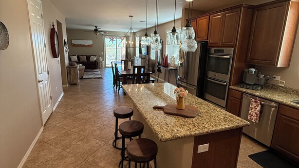 A spacious kitchen with a large island, bar stools, and modern appliances. - Dove Mountain Perserve, gated, dog friendly home. (Marana)