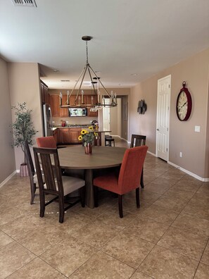 A spacious dining area with a central island, wooden chairs, and a chandelier. - Dove Mountain Perserve, gated, dog friendly home. (Marana)