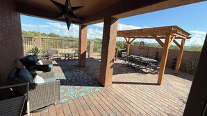 A covered patio with outdoor furniture, a star-shaped hanging light, and a pergola. - Dove Mountain Perserve, gated, dog friendly home. (Marana)