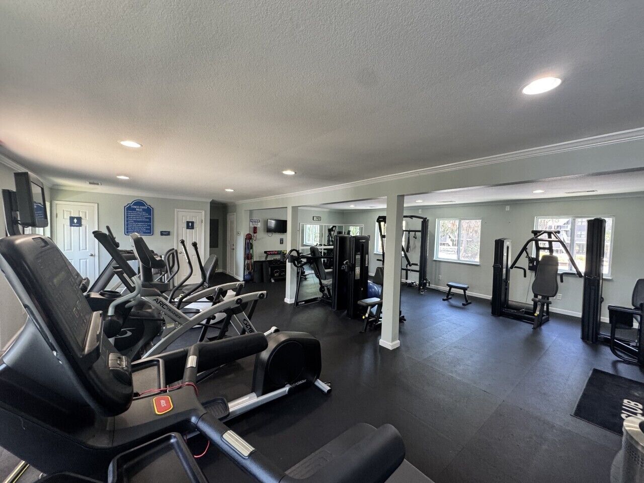 Une salle de sport équipée de divers appareils d’exercice, notamment des tapis de course et des appareils de musculation.