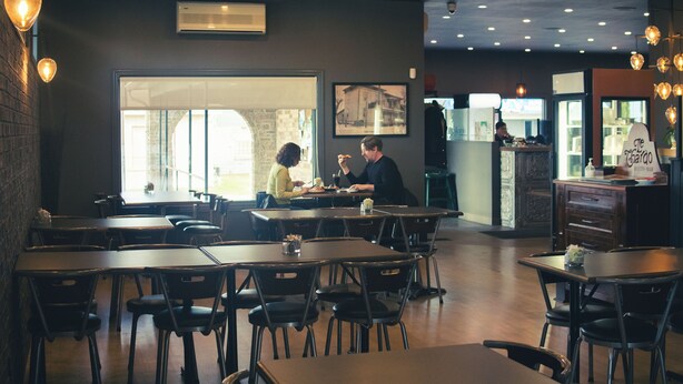 A restaurant with multiple tables and chairs, a large window, and a counter area. - Auberge Le Chardo Inn (Alfred)