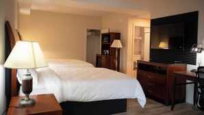 A hotel room with two beds, a desk, a television, and a wardrobe. - Auberge Le Chardo Inn (Alfred)
