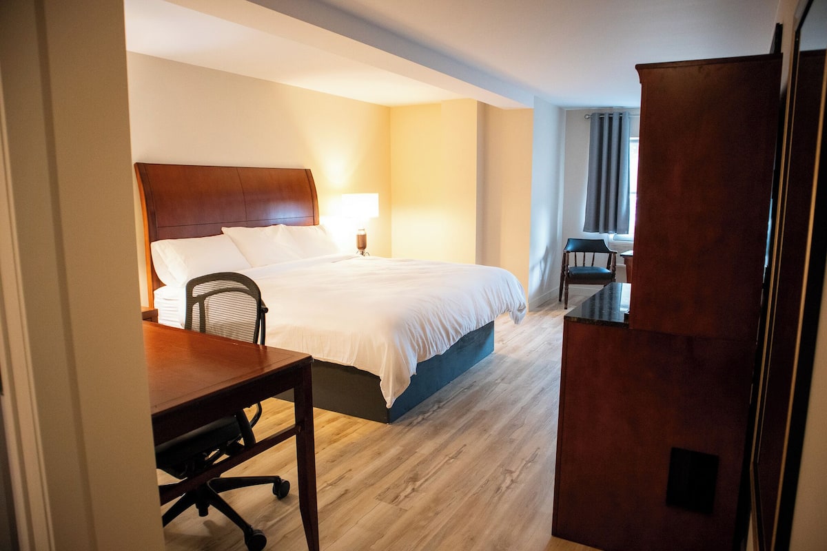 A hotel room with a bed, a desk, and a chair.
