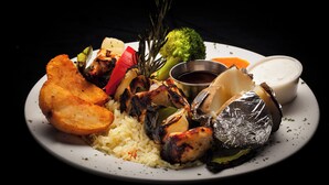 A plate of food with grilled chicken, vegetables, and rice. - Auberge Le Chardo Inn (Alfred)