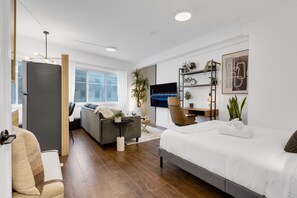 Une chambre à coucher moderne et bien éclairée, avec un grand lit, un canapé, un bureau et une télévision.