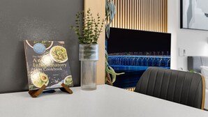 A modern office space with a white table, a plant in a clear vase, and a book titled "The Essential Anti-Inflammatory Diet Cookbook" on a stand.