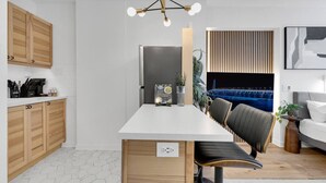 A modern kitchen with wooden cabinets, a white countertop, and a black chair.