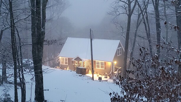 Een huis met een sneeuwbedekte kap en een zichtbare trap naar de ingang.