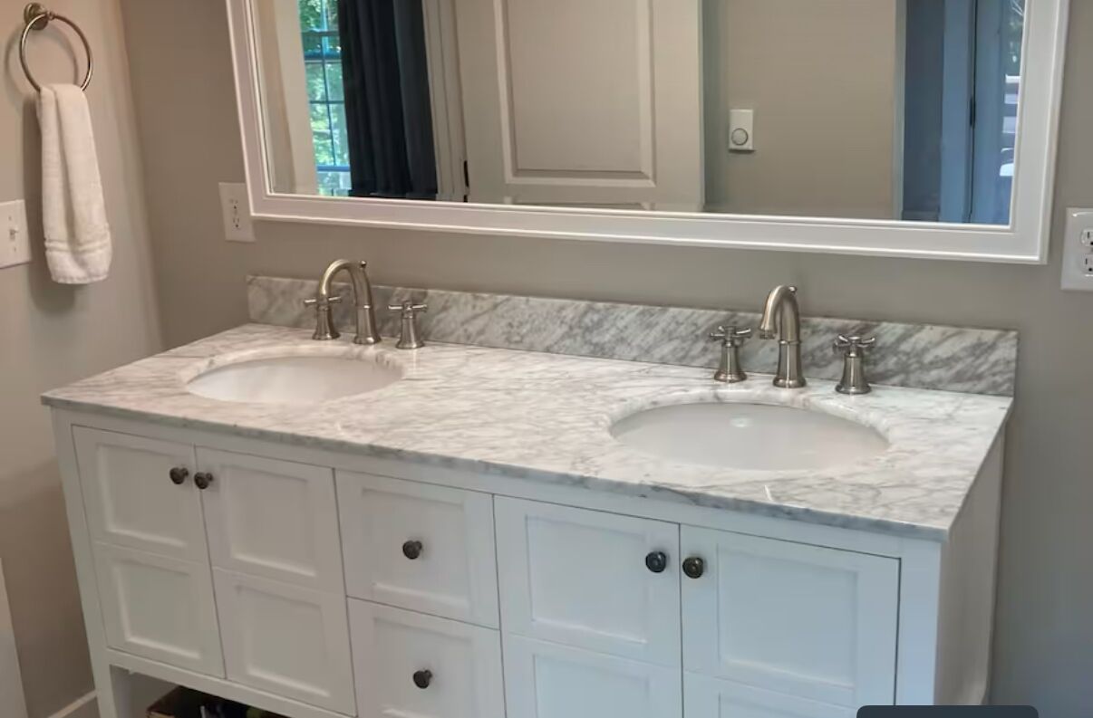 Une salle de bain avec deux lavabos, un grand miroir et des meubles blancs.