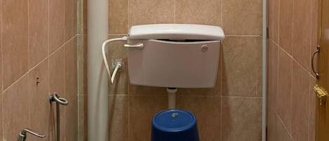 A small bathroom with pink walls, a white toilet, and a blue trash bin.