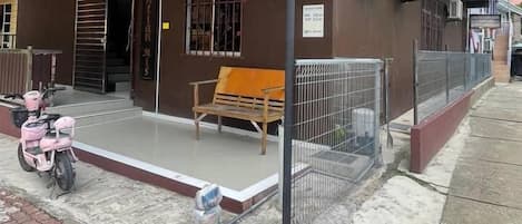 Un edificio de dos pisos con un porche cubierto y una banca.