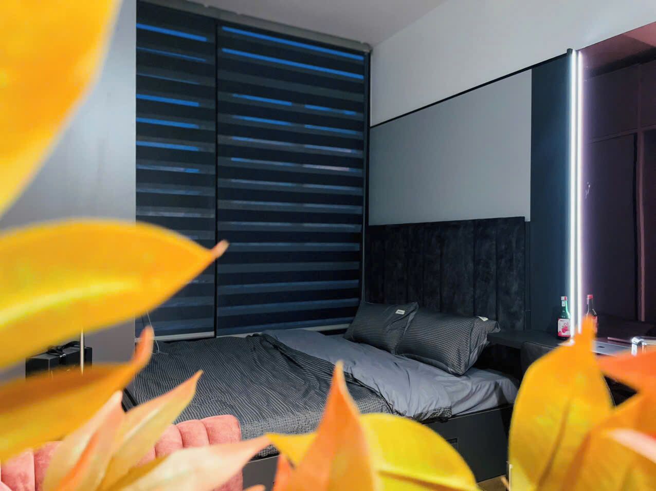 Ein modernes Schlafzimmer mit Bett, dunklem Kopfteil und einem Fenster mit Jalousien.