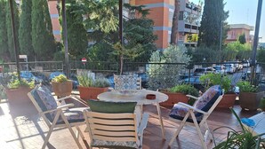 An outdoor seating area with chairs and tables, surrounded by potted plants and overlooking a parking area. - A Casa di Noele (Roma)