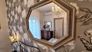 A room with a large octagonal mirror on the wall, a wooden dresser, and a chandelier. - A Casa di Noele (Roma)