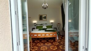 A bedroom with a wooden bed, green pillows, a chandelier, a painting on the wall, and a patterned floor. - Tiranoexpress 2 floor (Tirano)
